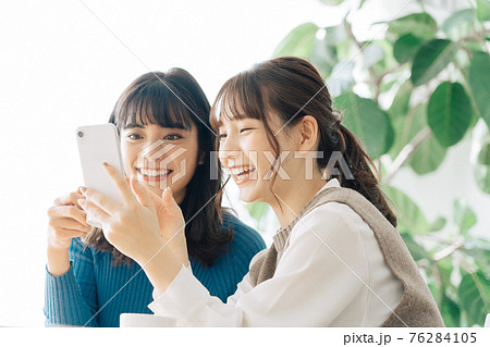 カフェでスマホを見る笑顔の女性2人組 76284105
