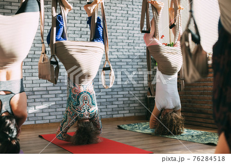 A group of young female yogis doing aerial yoga in hammocks at a fitness club. Aero yoga, sports, fitness 76284518