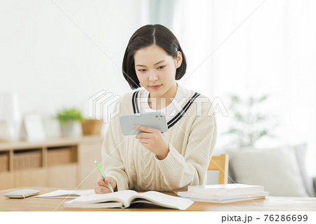 スマホを見ながら勉強をする高校生の写真素材