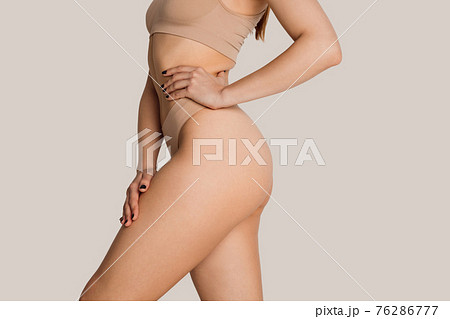 Beautiful female body in nude color underwear over grey background. Beautiful female body in nude color underwear over grey background. 76286777