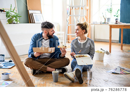 Couple eating lunch indoors at home, relocation, diy and food delivery concept. Couple eating lunch indoors at home, relocation, diy and food delivery concept. 76286778