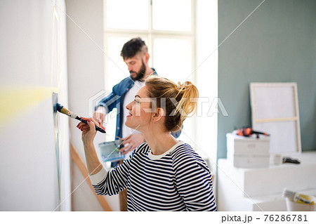 Mid adults couple painting wall indoors at home, relocation and diy concept. Mid adults couple painting wall indoors at home, relocation and diy concept. 76286781