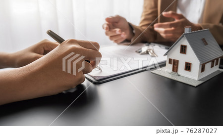 House model with agent and customer discussing for contract to buy, get insurance or loan real estate or property. House model with agent and customer discussing for contract to buy, get insurance or loan real estate or property. 76287027