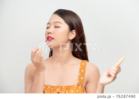 Attractive and beautiful Asian girl paint lips a beige lipstick 76287490