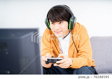 部屋でネットゲームをプレイする男性の写真素材