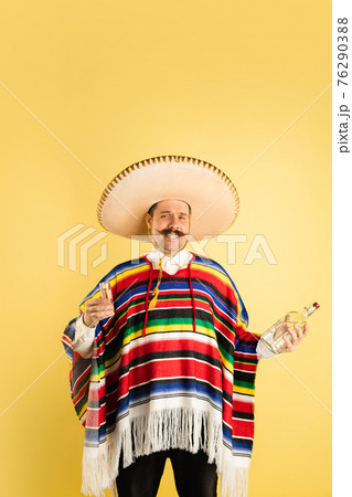 Portrait of happy man in bright garment, poncho isolated over yellow background 76290388