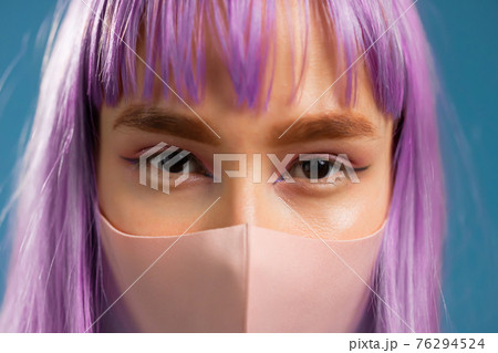 Young hipster woman in protective mask. Close-up portrait of fashion model with dyed violet 76294524