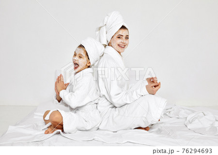 mother and daughter are sitting with towels on head and facial mask. 76294693