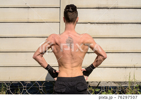 Back view of young handsome fighter man with lean muscular body outdoors 76297507