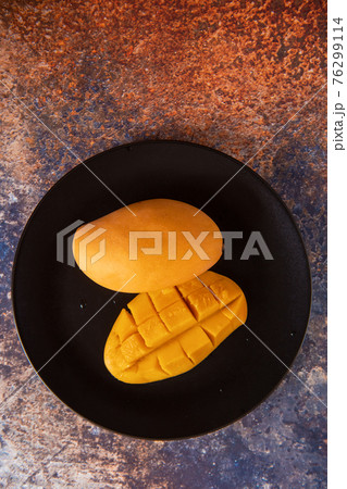 Fresh yellow mango fruit in a black plate 76299114