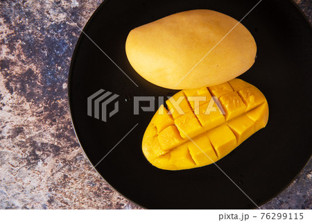 Fresh yellow mango fruit in a black plate 76299115