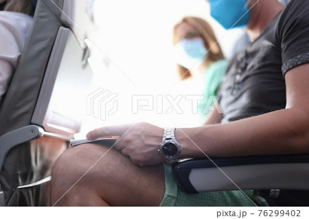 People in medical protective masks are sitting in aircraft cabin People in medical protective masks are sitting in aircraft cabin 76299402