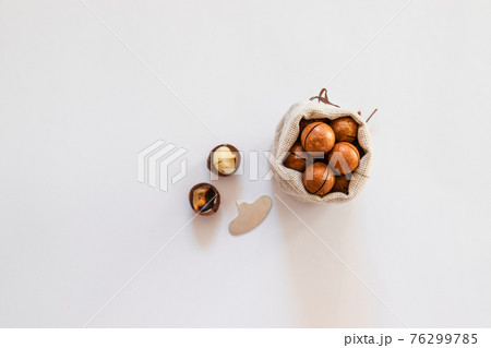 Raw macadamia nuts in canvas bowl on a white solid background. Minimal flat composition 76299785