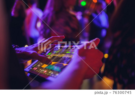 DJ playing music at mixer on colorful blurred background. 76300745