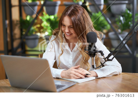Smiling woman communicating with followers online by laptop. Smiling woman communicating with followers online by laptop. 76301613