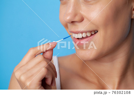 Woman uses brushes to clean the interdental spaces 76302108
