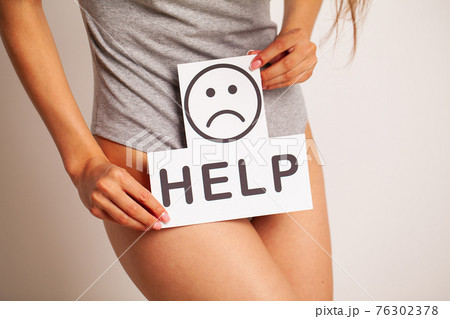 Young woman holds paper with help above crotch. 76302378