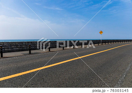 海岸沿いの曲がった道路とそれを示す標識 76303145