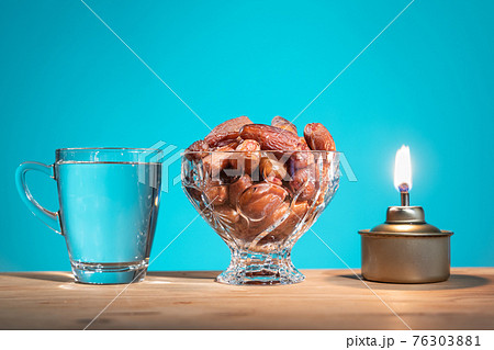 Muslim iftar of breaking of fast food during Ramadan month with preserved sweet dates and water. Pelita oil lamp as prop. Muslim iftar of breaking of fast food during Ramadan month with preserved sweet dates and water. Pelita oil lamp as prop. 76303881