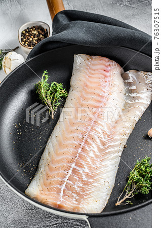 Raw cod loin with herbs in a frying pan. Gray background. Top view 76307515
