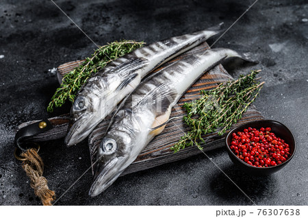 Raw icefish on a wooden cutting board. Black background. Top view Raw icefish on a wooden cutting board. Black background. Top view 76307638