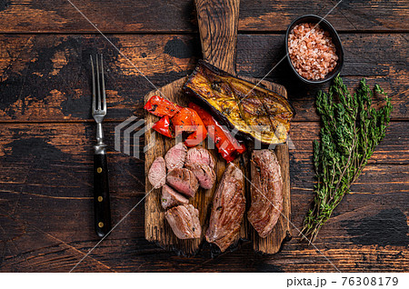 Roasted lamb tenderloin Fillet Meat steak on wooden cutting board. Dark wooden background. Top view 76308179