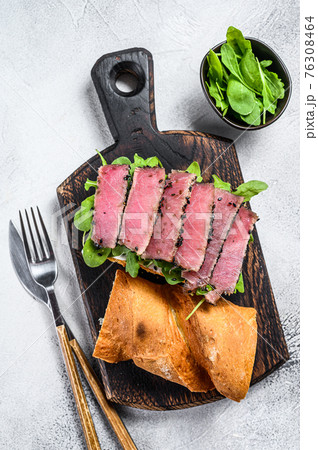 Tuna steak sandwich in a baguette with arugula. White background. Top view 76308464