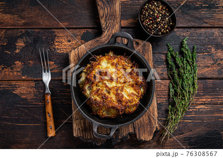 Fried Potato pancakes or Fritters with herbs in a pan. Dark wooden background. Top view 76308567