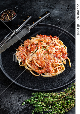 Feta pasta with Oven baked cherry tomatoes on a plate. Black background. Top view Feta pasta with Oven baked cherry tomatoes on a plate. Black background. Top view 76308772