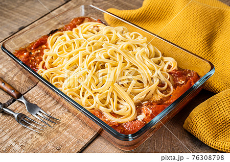 Oven roasted feta pasta with tomatoes in baking dish. Wooden background. Top view Oven roasted feta pasta with tomatoes in baking dish. Wooden background. Top view 76308798