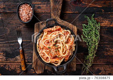 Trendy baked Feta pasta with Oven roasted tomatoes and cheese in a pan. Dark wooden background. Top view 76308875