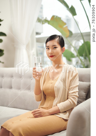 Beautiful young woman drinking water at home 76309904