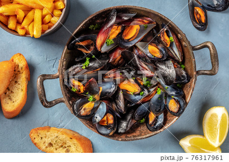 Mussels in a pan, with French fries, toasted bread, and lemon Mussels in a pan, with French fries, toasted bread, and lemon 76317961