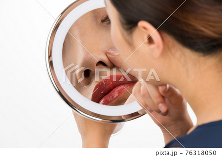 鏡で鼻を見る女性 76318050