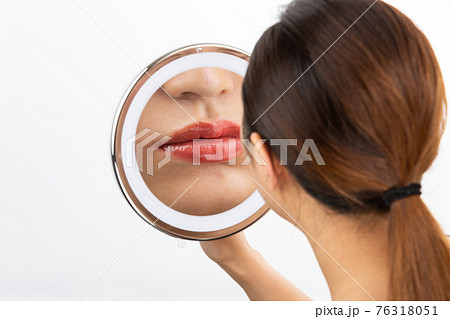 鏡で唇を見る女性 76318051