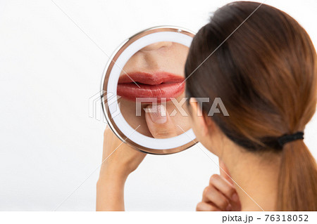 鏡で唇を見る女性 76318052