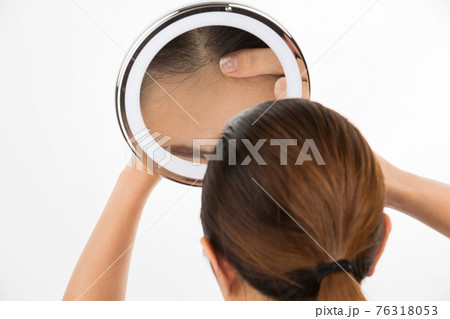鏡で頭皮を見る女性 76318053