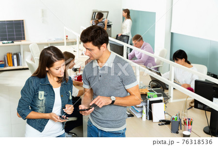 Male and female office co-workers having conversation at desk in office Male and female office co-workers having conversation at desk in office 76318536