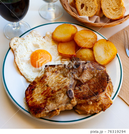 Pork chop with potatoes and scrambled eggs 76319294