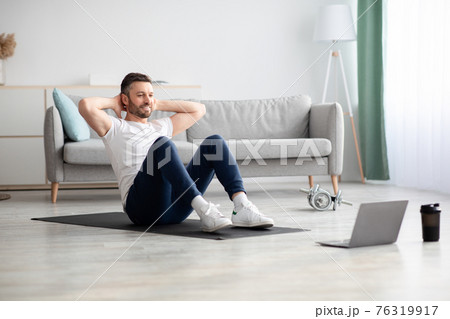 Smiling man working on abs, using laptop 76319917