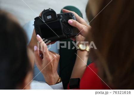 Two women hold camera in their hands and press buttons Two women hold camera in their hands and press buttons 76321616