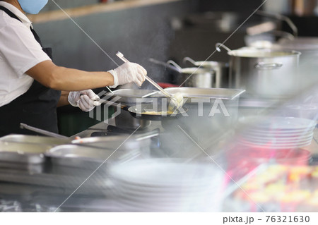 Cook prepares food in frying pan in kitchen 76321630