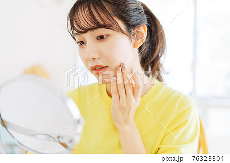 肌荒れを見る女性 76323304