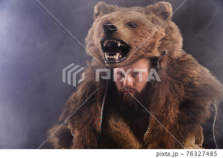 Low key portrait of a bearded war shaman in bearskin with an ancient ax in his hands. High quality cosplay of the ancient werewolf war 76327485