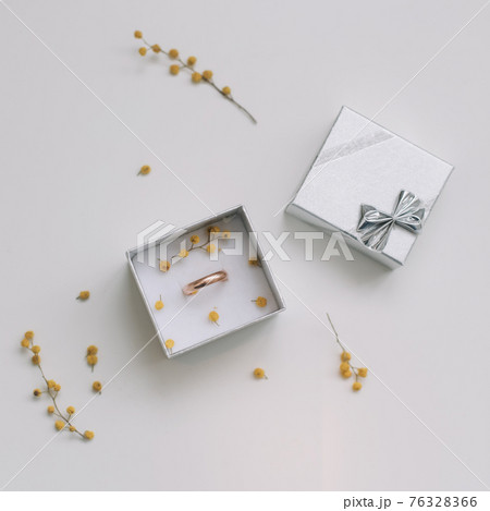Box with golden engagement ring on flowers background, top view. Wedding, Marriage proposal concept 76328366