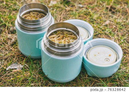 Warm food in a thermos standing on the grass Warm food in a thermos standing on the grass 76328642