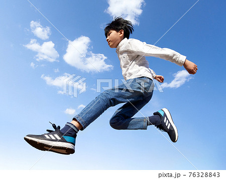 青空を背景にジャンプする少年 76328843