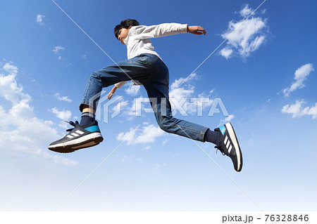 青空を背景にジャンプする少年 76328846