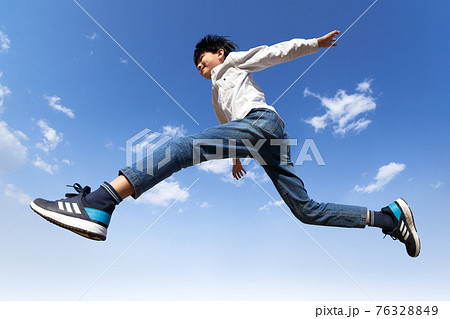 青空を背景にジャンプする少年 76328849