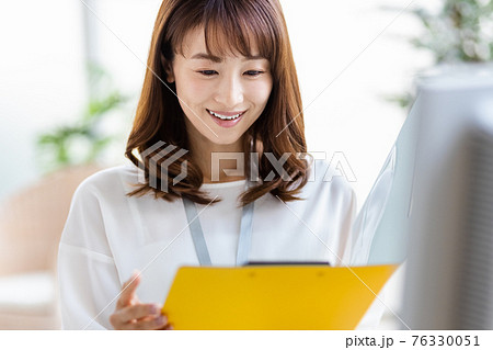 明るい室内でデスクワーク中の女性 76330051